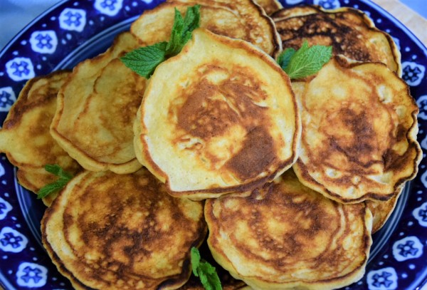 Pile of cheese pancakes on blue and white plate garnished with mint